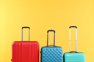 Different packed suitcases on yellow background, space for text. Travel luggage