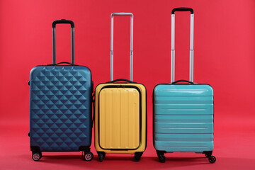 Different packed suitcases on red background. Travel luggage
