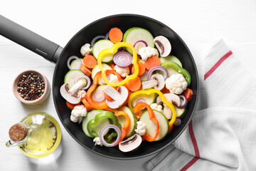 Frying pan with mix of vegetables, mushrooms and spices on white wooden table, top view