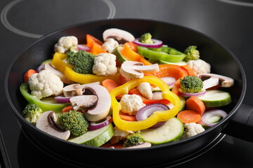 Frying pan with mix of vegetables and mushrooms on cooktop, closeup