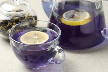 Delicious butterfly pea flower tea with lemon on gray textured table, closeup