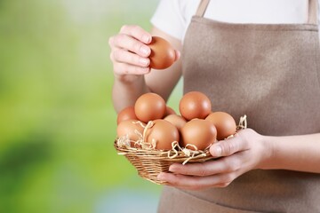 Woman with basket of eggs on blurred background, closeup. Space for text