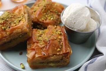 Delicious baklava with crushed nuts and ice cream on table, closeup