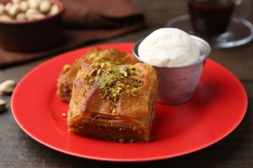 Tasty baklava with chopped nuts and scoop of ice cream on wooden table, closeup