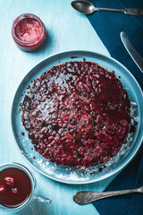 Cherry chocolate clafutis on a light blue plate. French pie according to a traditional recipe. A quick homemade dessert. Vertical photo