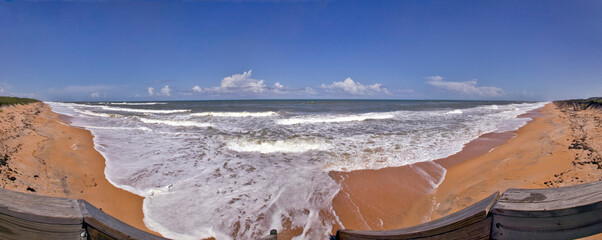 Panoramic beach view of sea foam and ocean surf rolling in over a deserted Flagler Beach, Florida, USA.