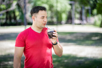 Latin man drinking mate in a park