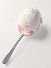 Scoop of creamy white ice cream on a stainless steel spoon resting on a light background
