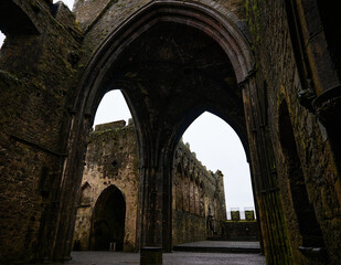 Interior view of the Rock of Cashel ruins in County Tipperary, Ireland. The medieval stone architecture features large Gothic archways and historic remnants, showcasing Ireland’s rich culture