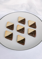 Delicious chocolate-dipped cookies arranged neatly on a white plate ready to enjoy during an afternoon snack