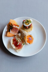 Elegant assortment of gourmet appetizers on a white plate served at a modern dining venue during an evening gathering