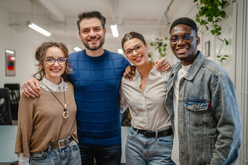 Portrait of business workers colleagues stand and hug in the office