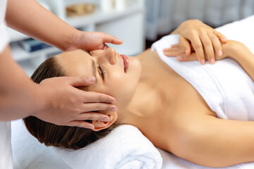 Caucasian woman enjoying relaxing anti-stress head massage and pampering facial beauty skin recreation leisure in dayspa modern light ambient at luxury resort or hotel spa salon. Quiescent