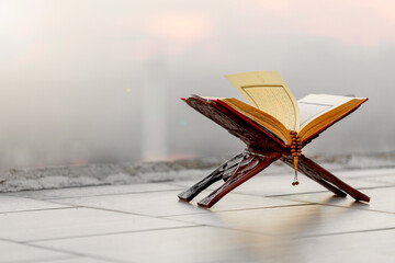 A serene moment of faith. A Quran and prayer beads rest against a backdrop of a tranquil nature...