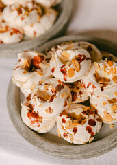 Delightful meringue cookies topped with almond slivers and strawberry sauce on a rustic plate