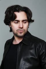 Portrait of bearded handsome man wearing black jacket and looking away indoor.