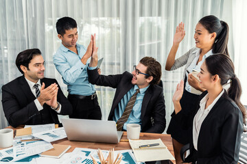 Group of happy businesspeople in high five gesture and successful efficient teamwork. Diverse race office worker celebrate after made progress on marketing planning in corporate office. Meticulous