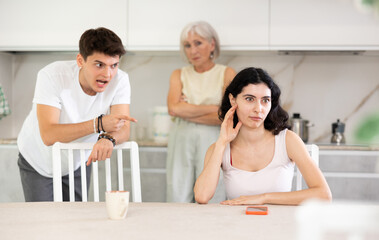 Fototapeta premium Young girl listens to swearing and accusations of inappropriate behavior from elderly mother and older brother