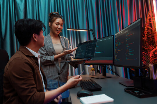 Serious of IT developers discussing intelligent website development coder system running data online two screens with laptop showing information network at neon light room at modern office. Infobahn.