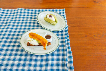 Matcha Green Tea Roll Cake and Salted caramel banana cake on blue classic checkered tablecloth texture,homemade bread cake,top view from above, space for text.