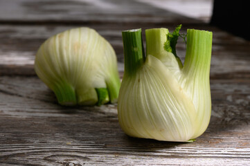 Freshly sliced fennel bulbs showcase vibrant green stalks on rustic wooden table during afternoon light