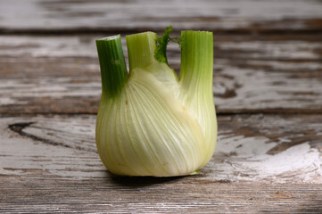 Fresh fennel bulb resting on rustic wooden table during sunny day with soft natural light