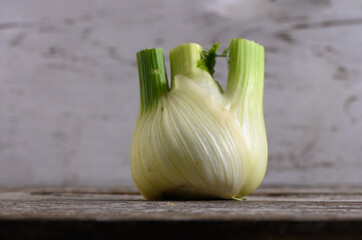 Unique fennel bulb resting on a rustic wooden table with a subtle background in soft natural light