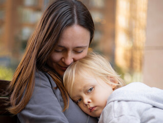 Obraz premium a three-year-old boy rested his head on his mother's shoulder, motherhood