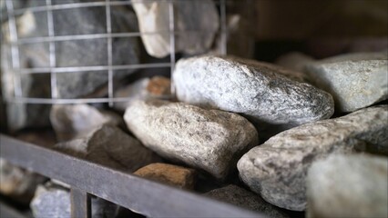 Stones for sauna stove heating on metal grid and wire basket
