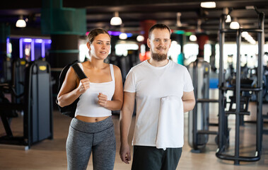 Fototapeta premium Young woman and young man going to workout together in gym