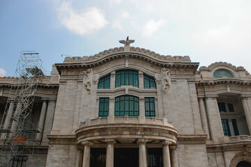 Costado del palacio de bellas artes retratado en un día soleado con pocas nubes.