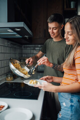 Lesbian couple preparing scrambled eggs for breakfast in modern kitchen