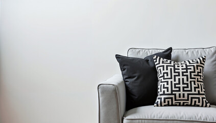 Minimalist black and white throw pillow with geometric designs placed on a sleek gray couch, with copy space for text