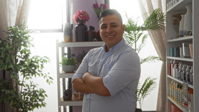 Young man smiling in a decor shop with indoor plants and shelves filled with vases and lotions in the background