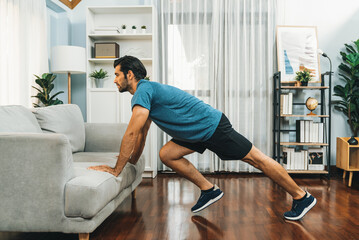 Fototapeta premium Athletic body and active sporty man using furniture for effective targeting muscle gain exercise at gaiety home exercise as concept of healthy fit body home workout lifestyle.