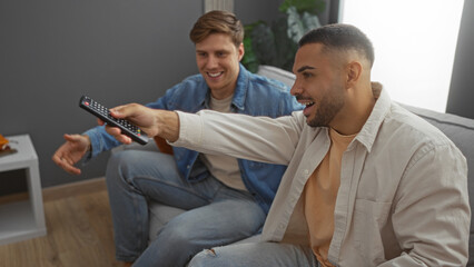 Fototapeta premium Men watching tv in a cozy living room, laughing and enjoying their time together, showing strong friendship and a relaxed atmosphere at home.