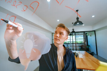 Professional caucasian businessman writing marketing idea by using mind map and sticky notes on glass board at modern meeting room. Creative business and planing concept. Closeup. Immaculate.