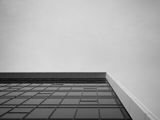A striking black and white photograph capturing the facade of a modern building with reflective windows mirroring the clouds in the sky, showcasing architectural detail and urban elegance.