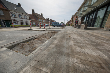 Construction work underway on a city street with uneven pavement and traffic cones in an urban area
