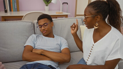 Woman talking to her son while sitting on a couch in their living room, showcasing a family moment filled with love and connection in an indoor setting