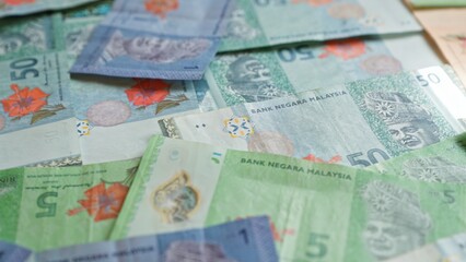 Malaysian banknotes of various denominations are scattered closely together, featuring vibrant colors and details indicating their currency value.