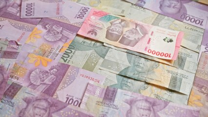 Indonesian rupiah banknotes arranged in a scattered pattern representing currency and financial concepts in indonesia.