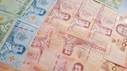 Thai baht banknotes from thailand in various denominations are arranged laid out, showcasing the country's currency.