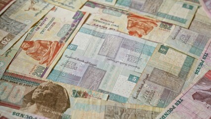 Egyptian banknotes, featuring currency denominations including pounds, scattered with intricate designs and colors emphasizing egyptian heritage and culture.