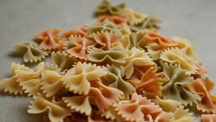 Colorful farfalle pasta scattered on a concrete surface, showcasing a variety of vibrant hues and creating a visually appealing food scene for culinary inspiration
