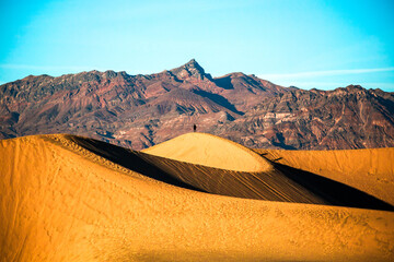 Silhouette of man enjoying the sunset with scenic view on Mesquite Flat Sand Dunes, Death Valley National Park, California, USA. Evening walk in Mojave desert with Amargosa Mountain Range in back