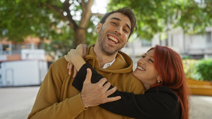 Woman embracing man in urban park, showcasing joyful couple sharing love and laughter together outdoors.