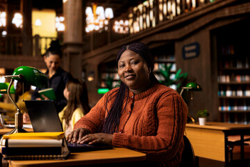 Portrait of confident tutor reviewing her notes and preparing teaching materials at a library desk, showcasing her dedication to pedagogy and mentoring. Providing academic support to her learners.