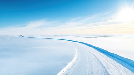 Fototapeta premium Bird's eye view of an expansive arctic landscape showcasing a winding snow-covered path under a bright blue sky with the sun shining down, highlighting the serene beauty of the white wilderness