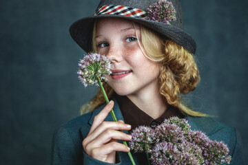 Studio portrait of a beautiful young girl with blonde hair and freckles on her face. She holds...